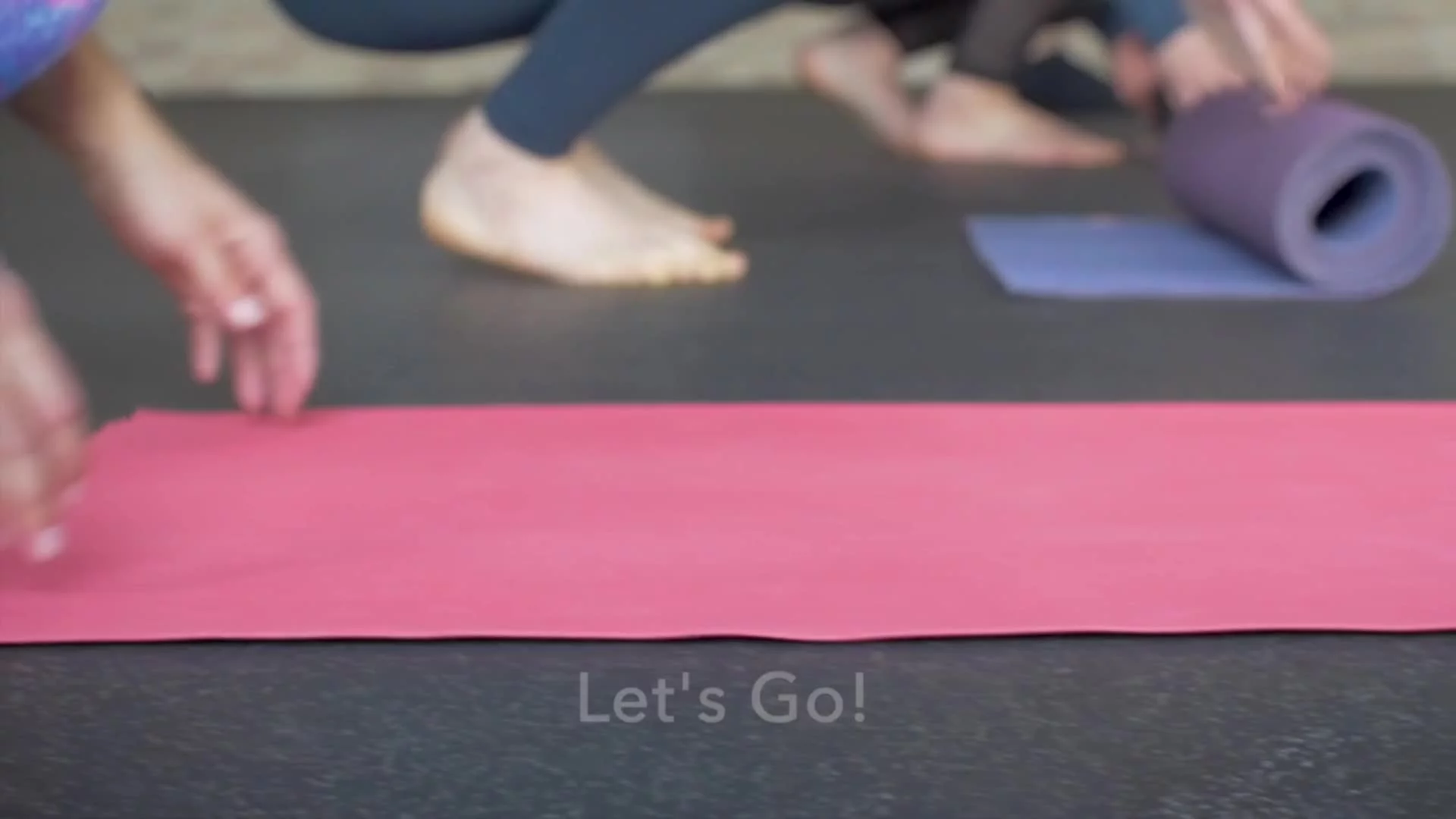 Close-up of people unrolling yoga mats with text “Let’s Go!” over image.