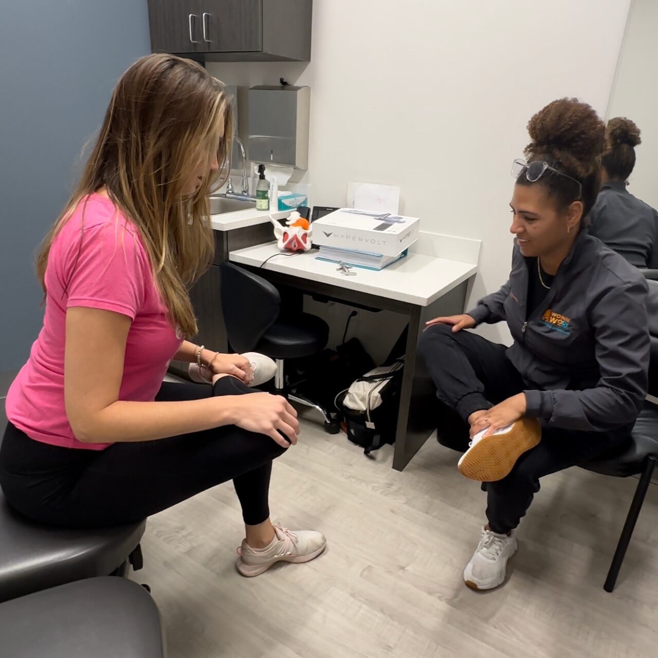 Healthcare professional examining a patient’s knee during a clinic visit.