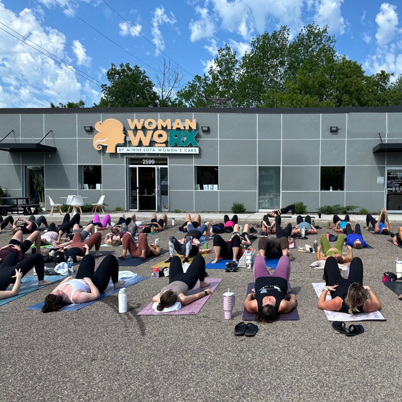 Group of women participating in outdoor fitness class in front of Woman WoRX.