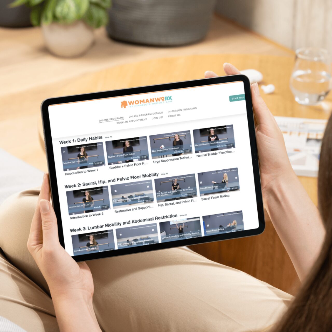 Person holding a tablet displaying Woman WoRX online program videos for pelvic health.